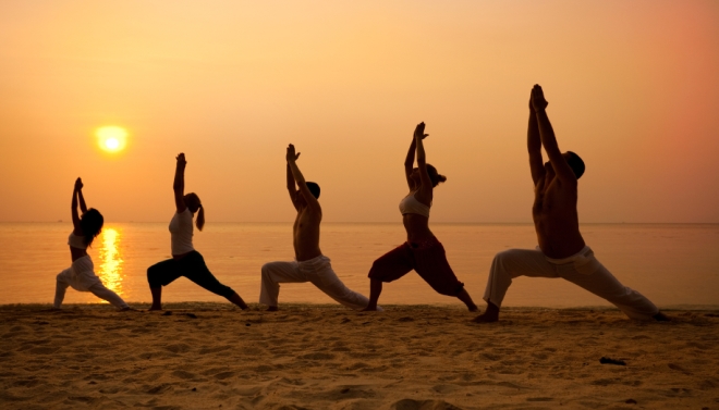 Group yoga on beach during sunrise